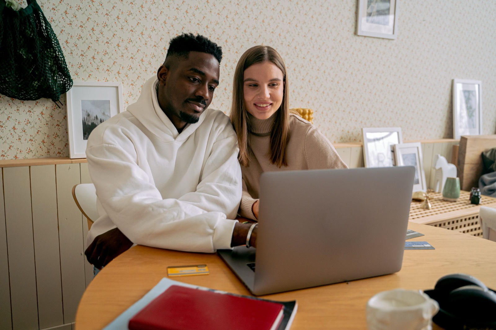 Smiling couple sitting together at a round table at home, looking at a laptop